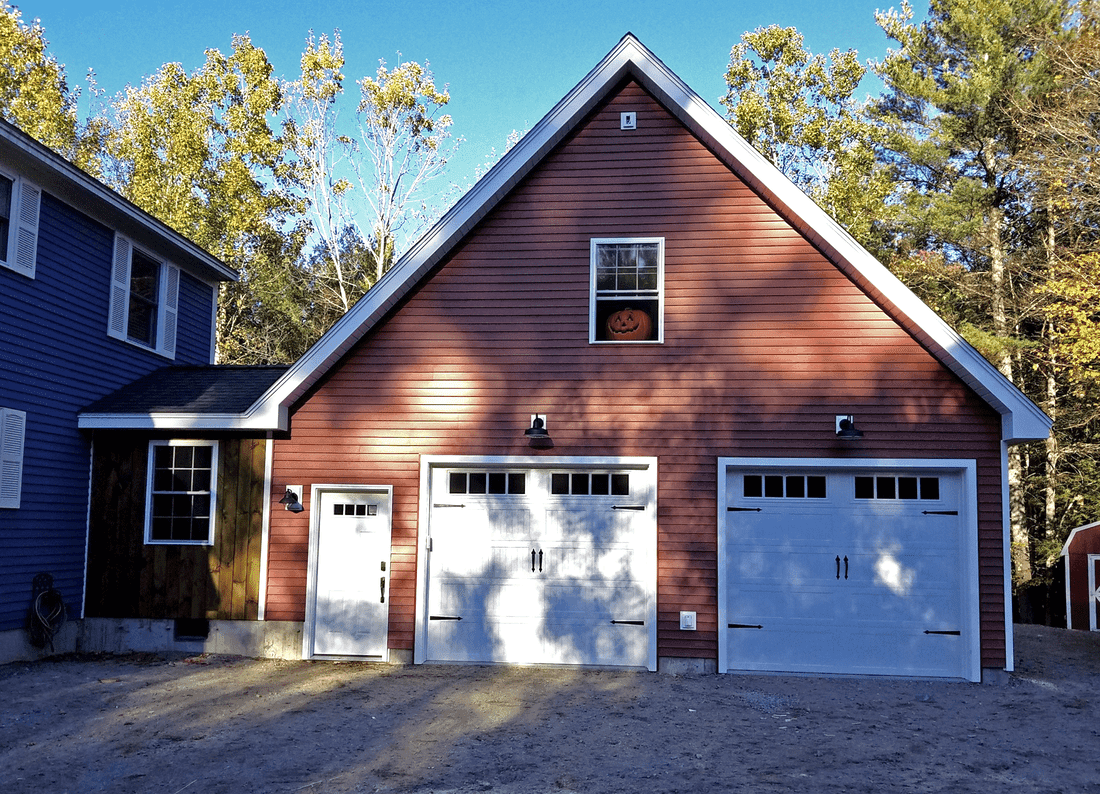 Barn red detached two car garage with a gable end and white carriage style doors