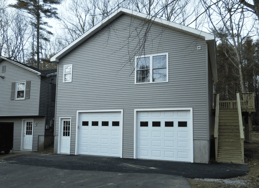 Two storey detached garage with living space above the bays, built beside an existing house
