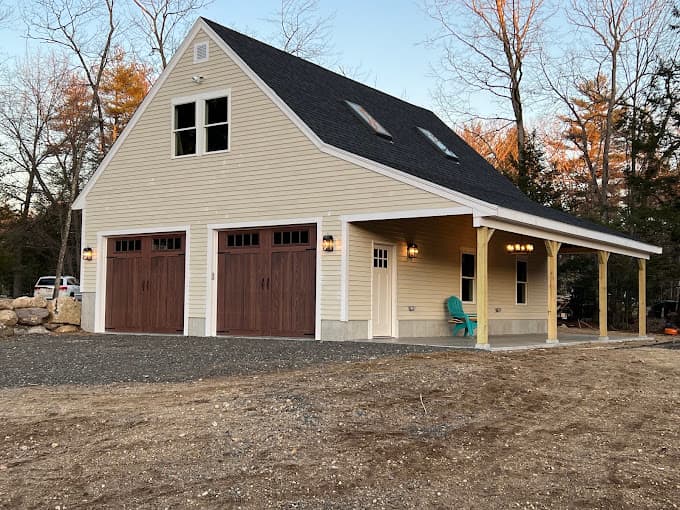 Two car detached garage with a loft, wood carriage doors and a covered porch along one side