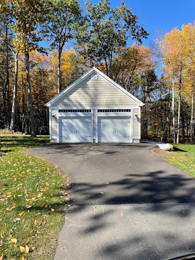 White two car detached garage with carriage doors at the end of a curved driveway